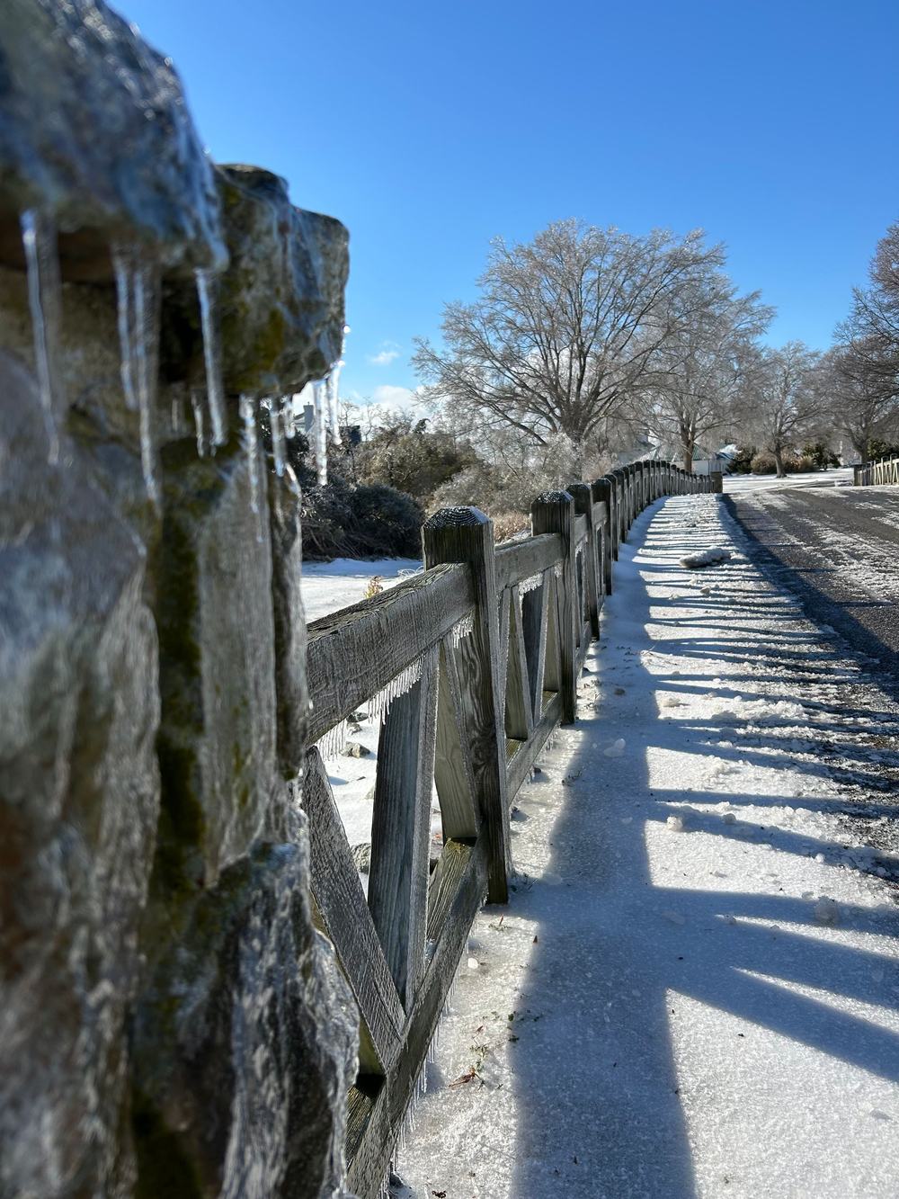 Icicles hanging from a split-rail fence after a freezing rain.