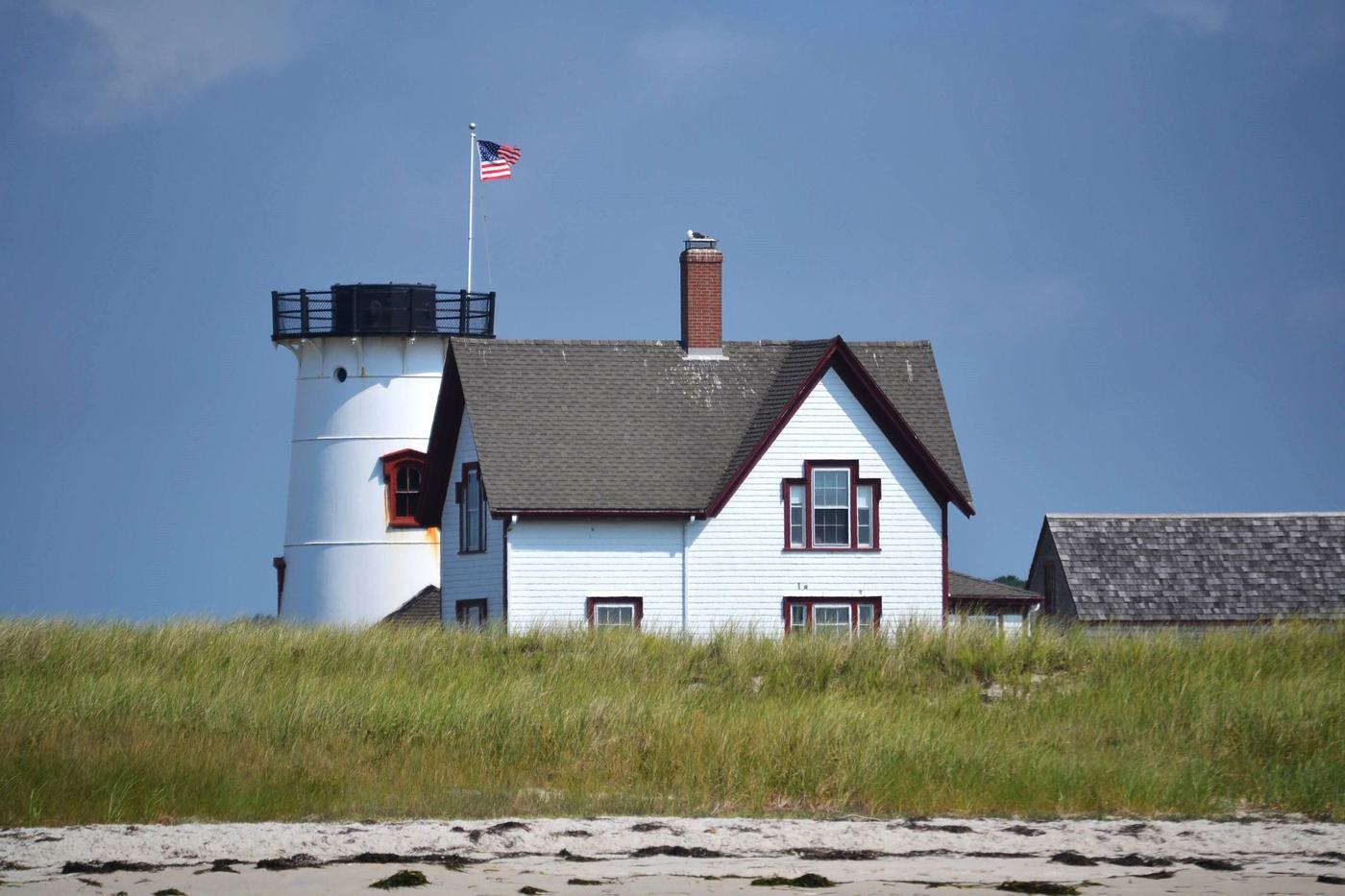 Stage Harbor lighthouse and keeper's house behind beach grass.